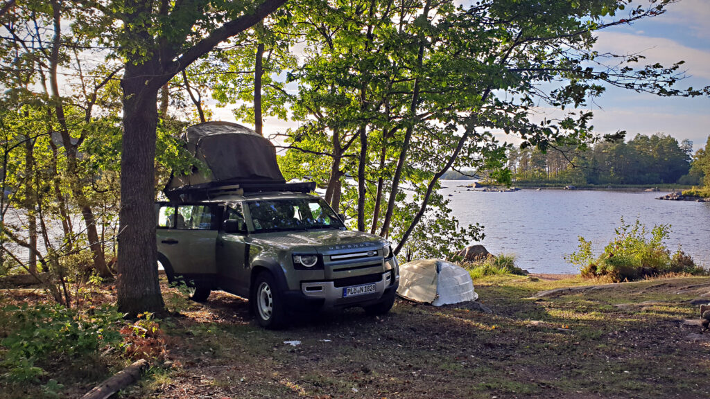 Land Rover Defender mit Dachzelt am see in Schweden