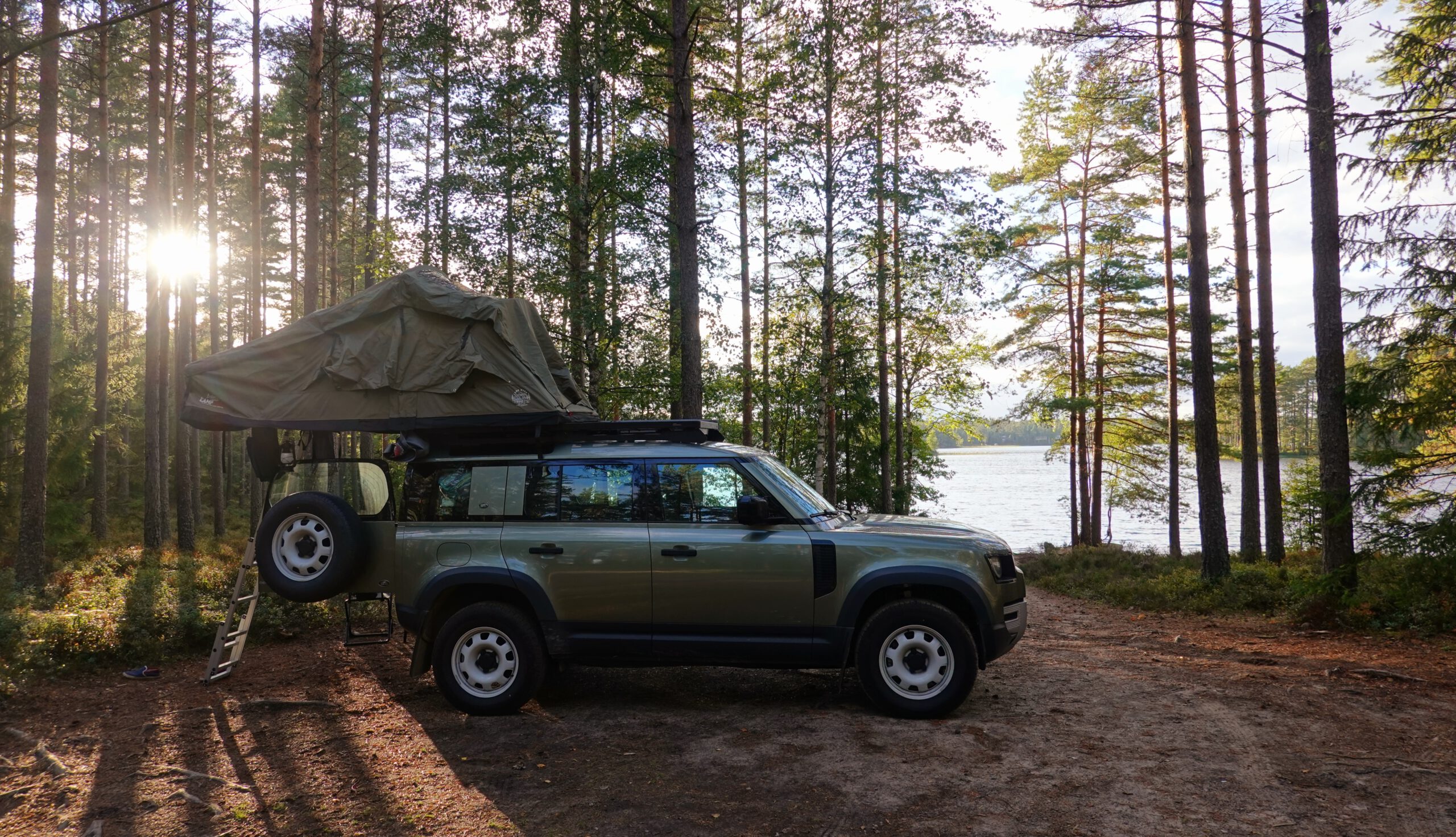 Defender-Camping in Sweden: Land Rover Defender with rooftoptent at a lake in Sweden